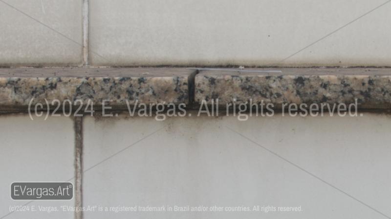 horizontal granite piece on dirty tile wall, urban, street, outdoors, daylight